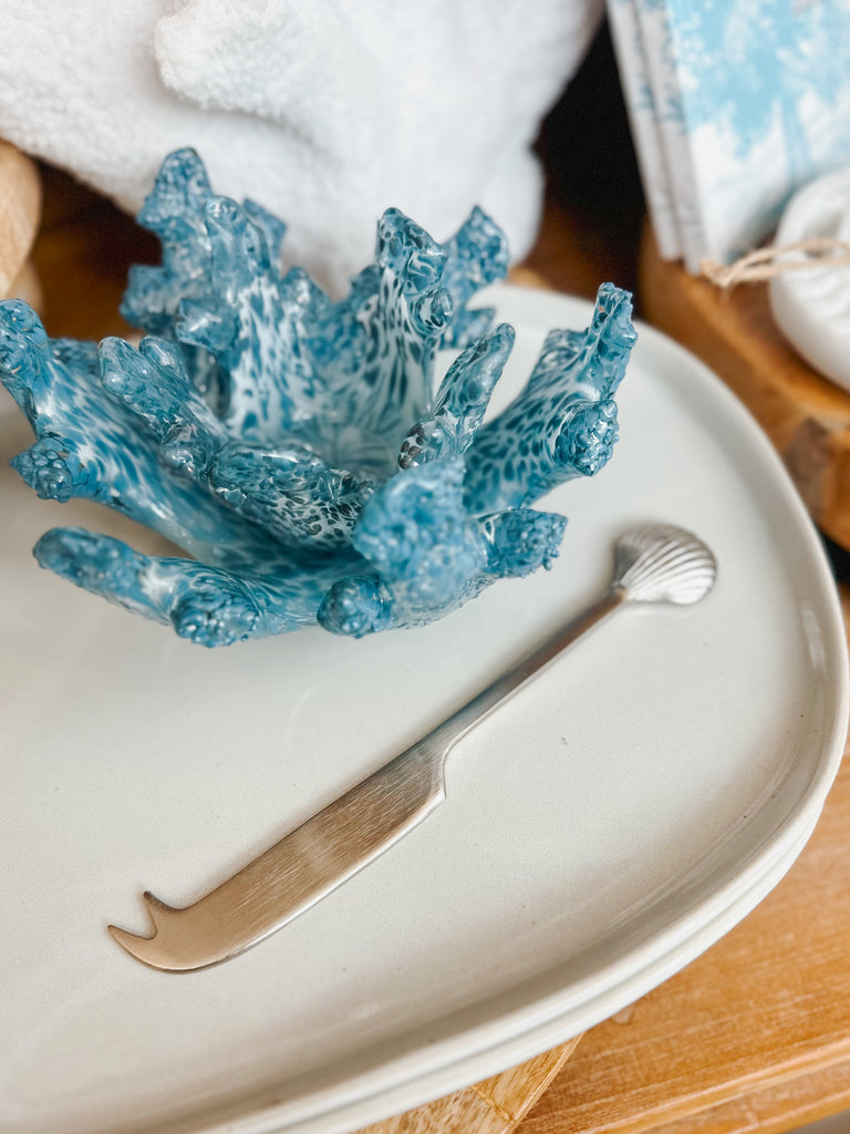 Blue coral-shaped dish with a silver nautilus cheese knife on a white plate